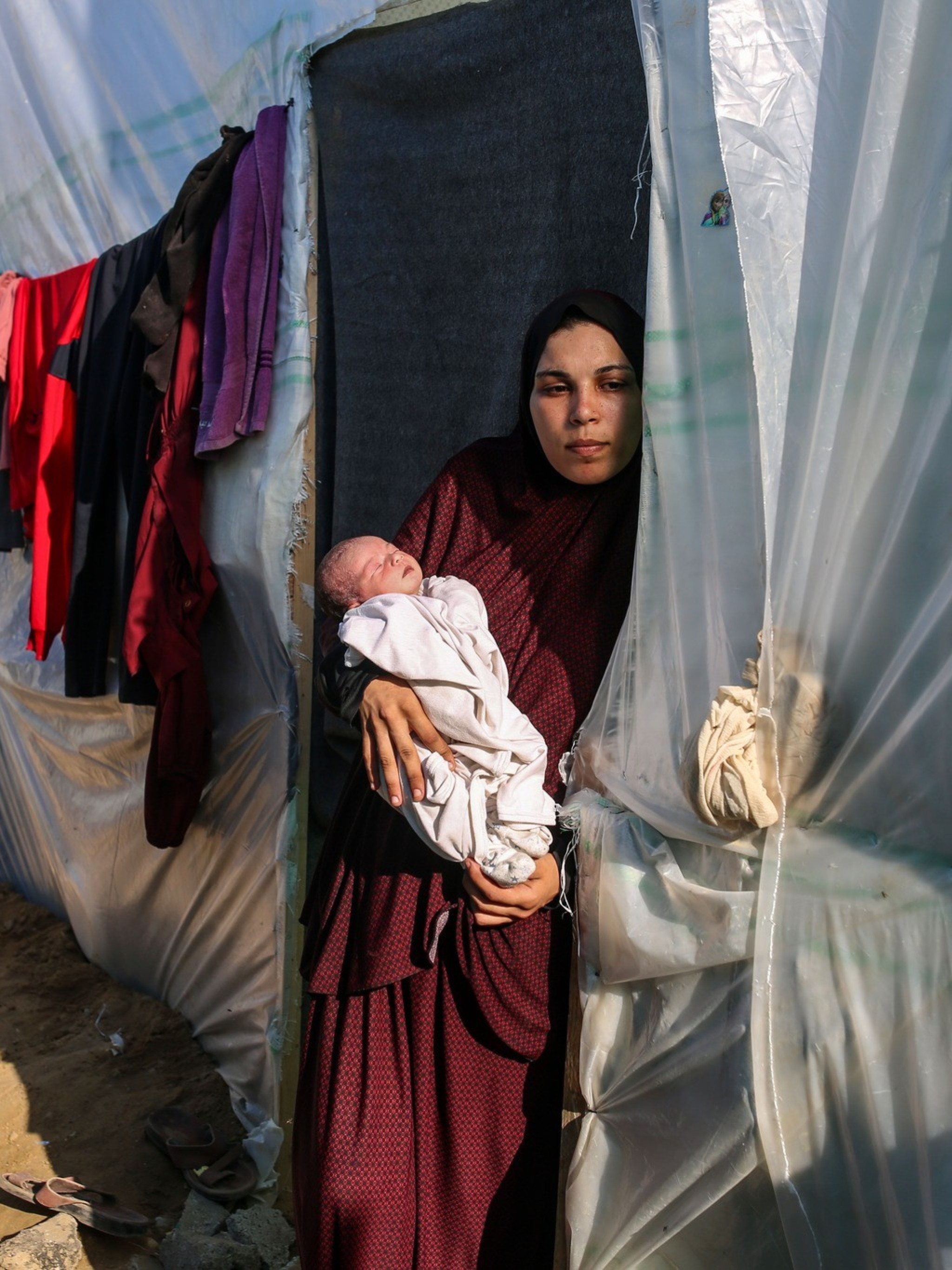 Frau mit Neugeborenem am Eingang zu einem Zelt in einem Flüchtlingslager im Gazastreifen, November 2023. Foto: Samar Abu Elouf