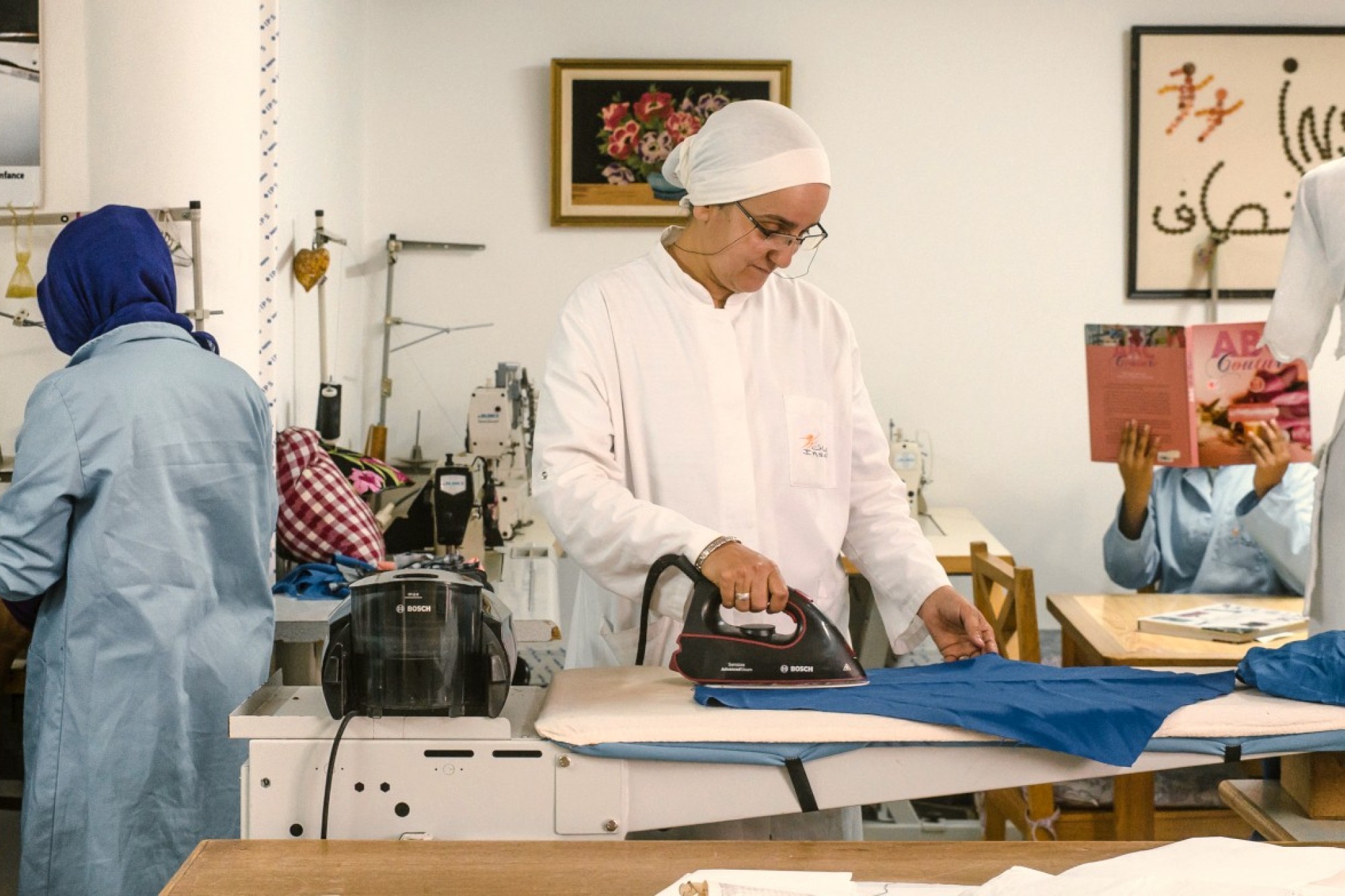 Frauen in Marokko arbeiten in einer Schneiderei und büglen, schneidern und nähen Kleider.