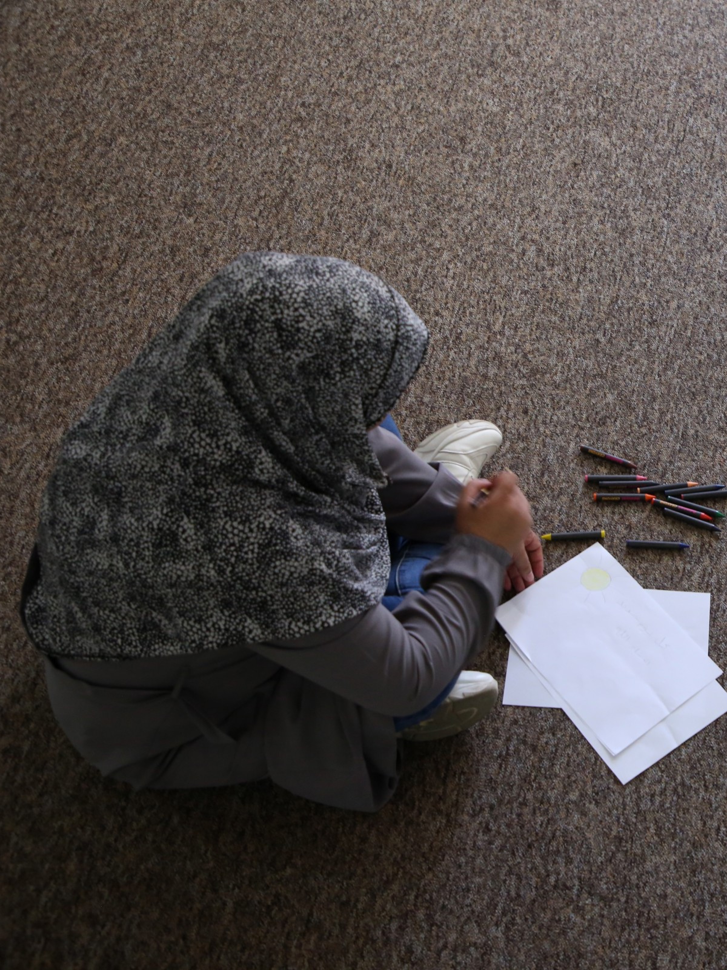 Frauenen in Palästina sitzen auf dem Boden mit Blätter und Stifte vor ihnen.