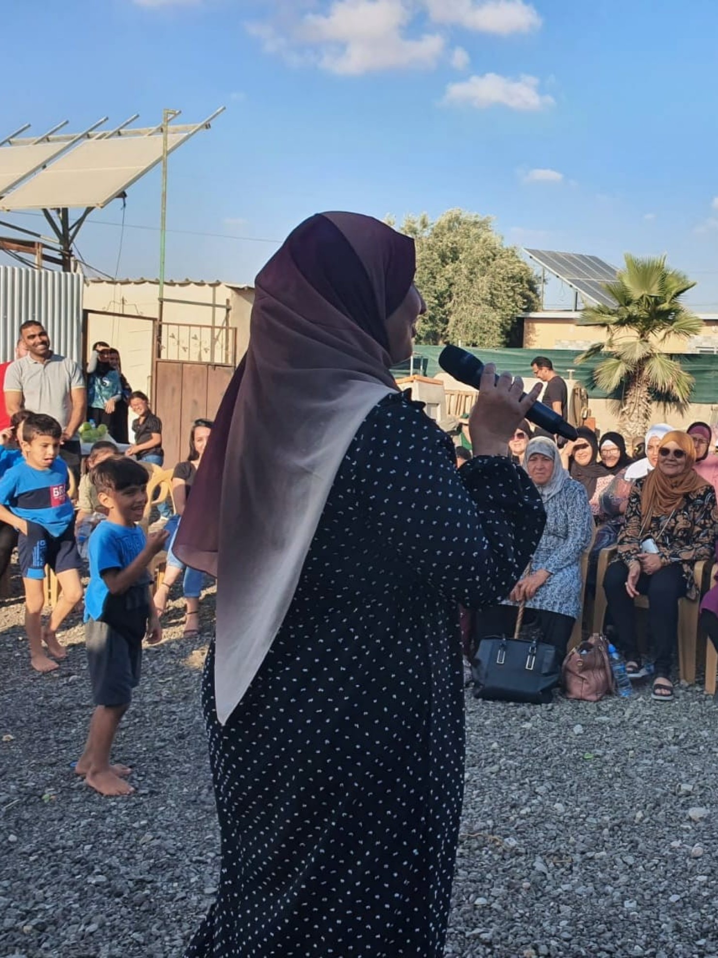 Frau mit Kopftuch in Israel spricht durch ein Mikrofon zu einer Gruppe von sitzenden Frauen